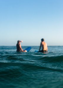 Two people sitting on surfboards in the water
