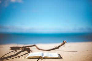 Open book on a sandy beach with ocean in background